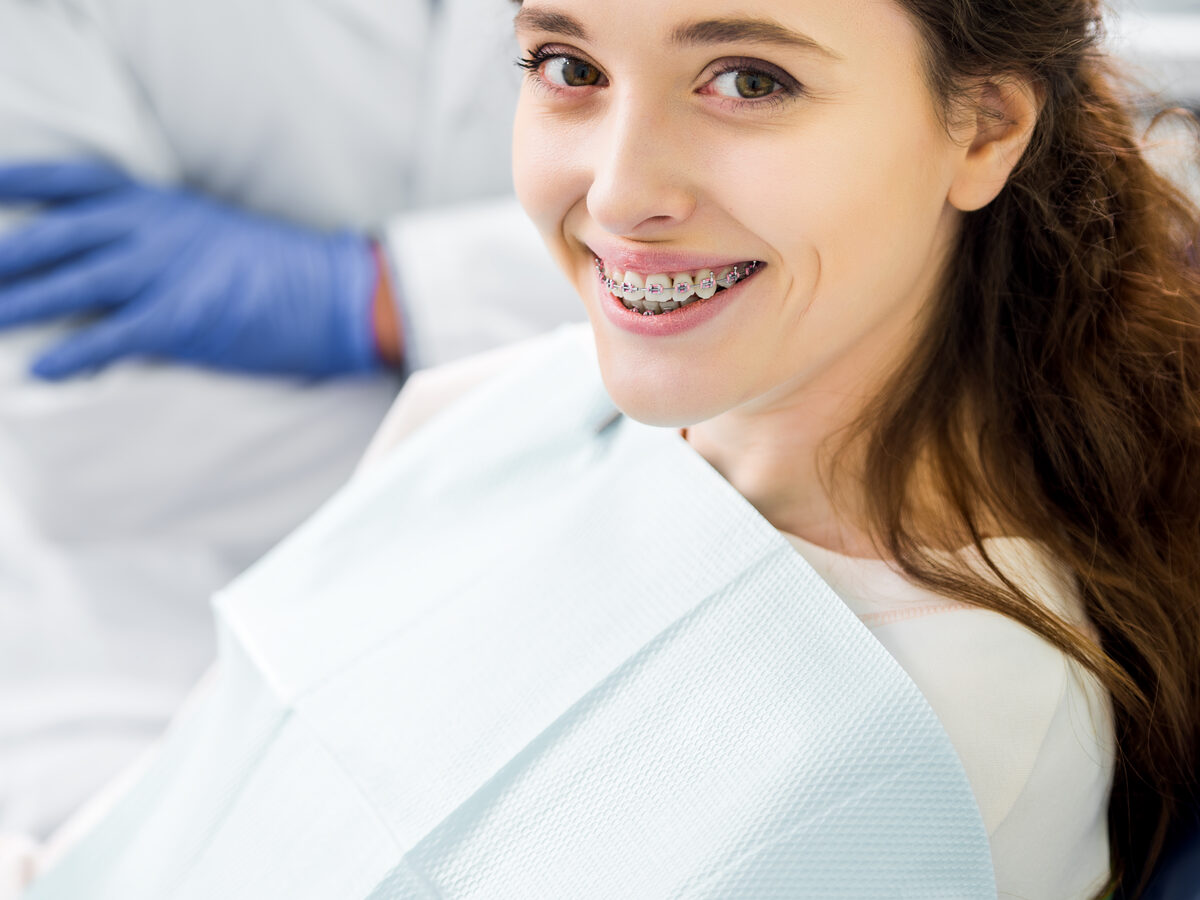 Smiling patient with orthodontic braces at a dental practice — dental practice marketing services